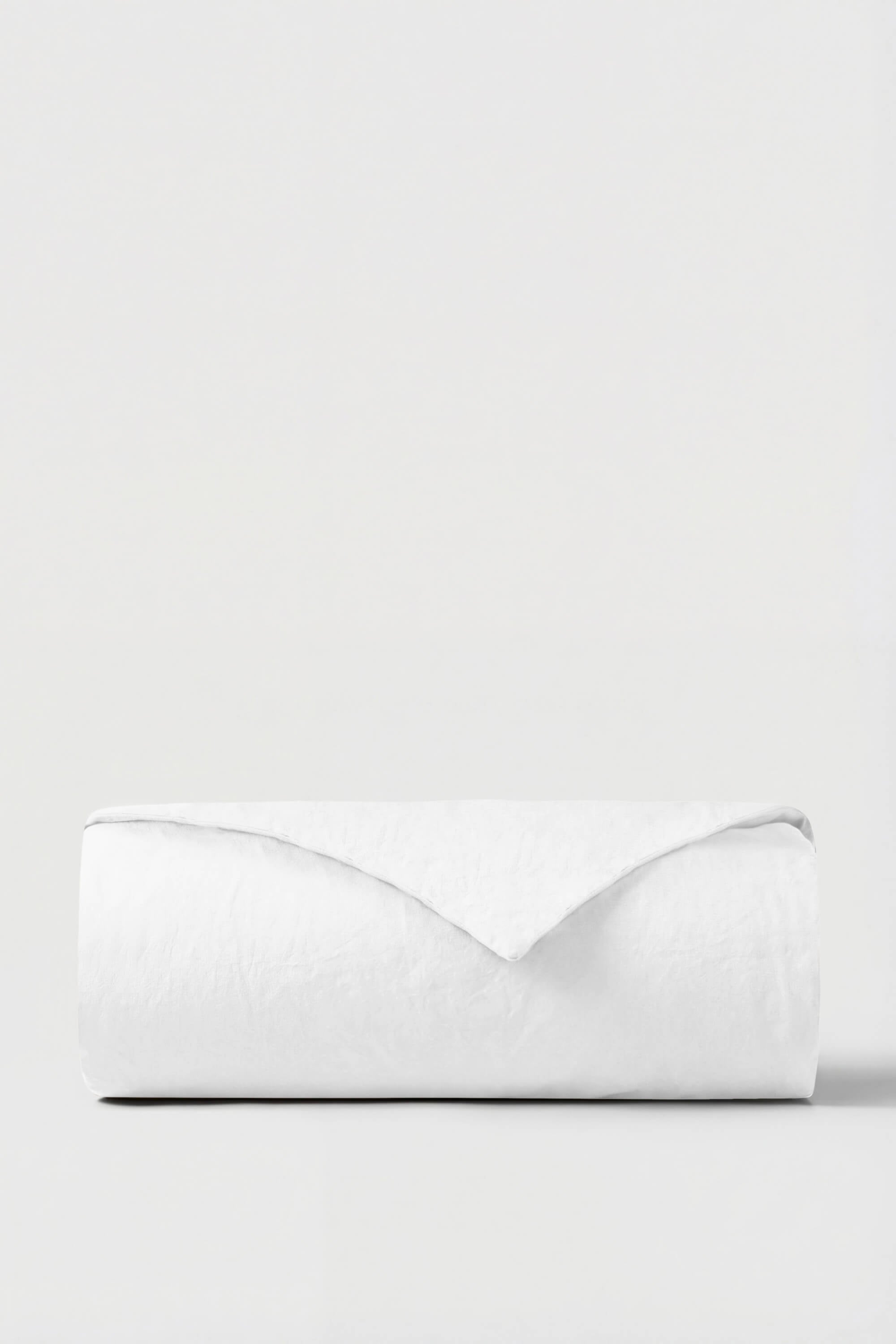 A crisp white percale duvet cover neatly rolled with a smooth minimalist design perfect for bedding updates