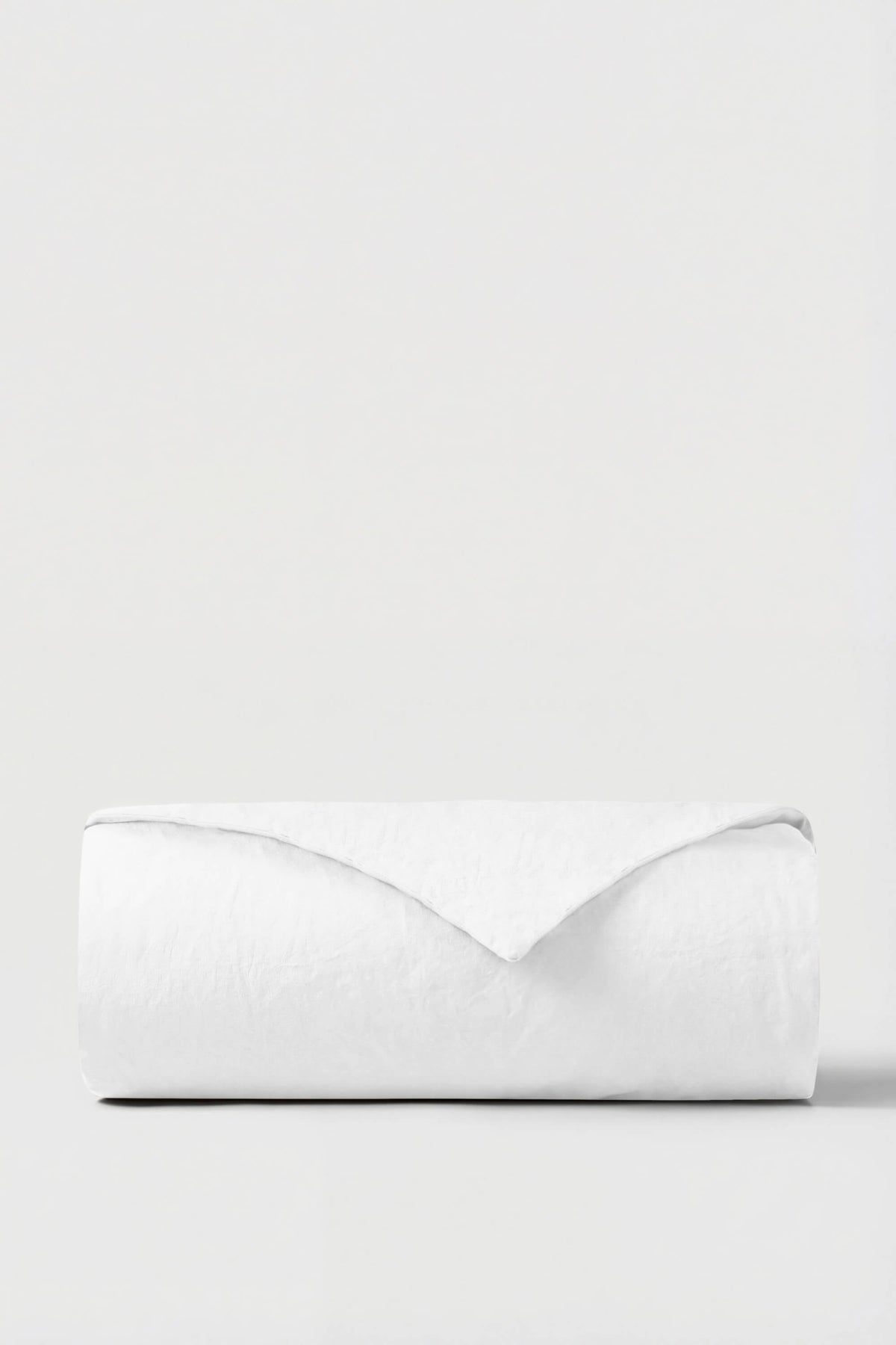 A crisp white percale duvet cover neatly rolled with a smooth minimalist design perfect for bedding updates