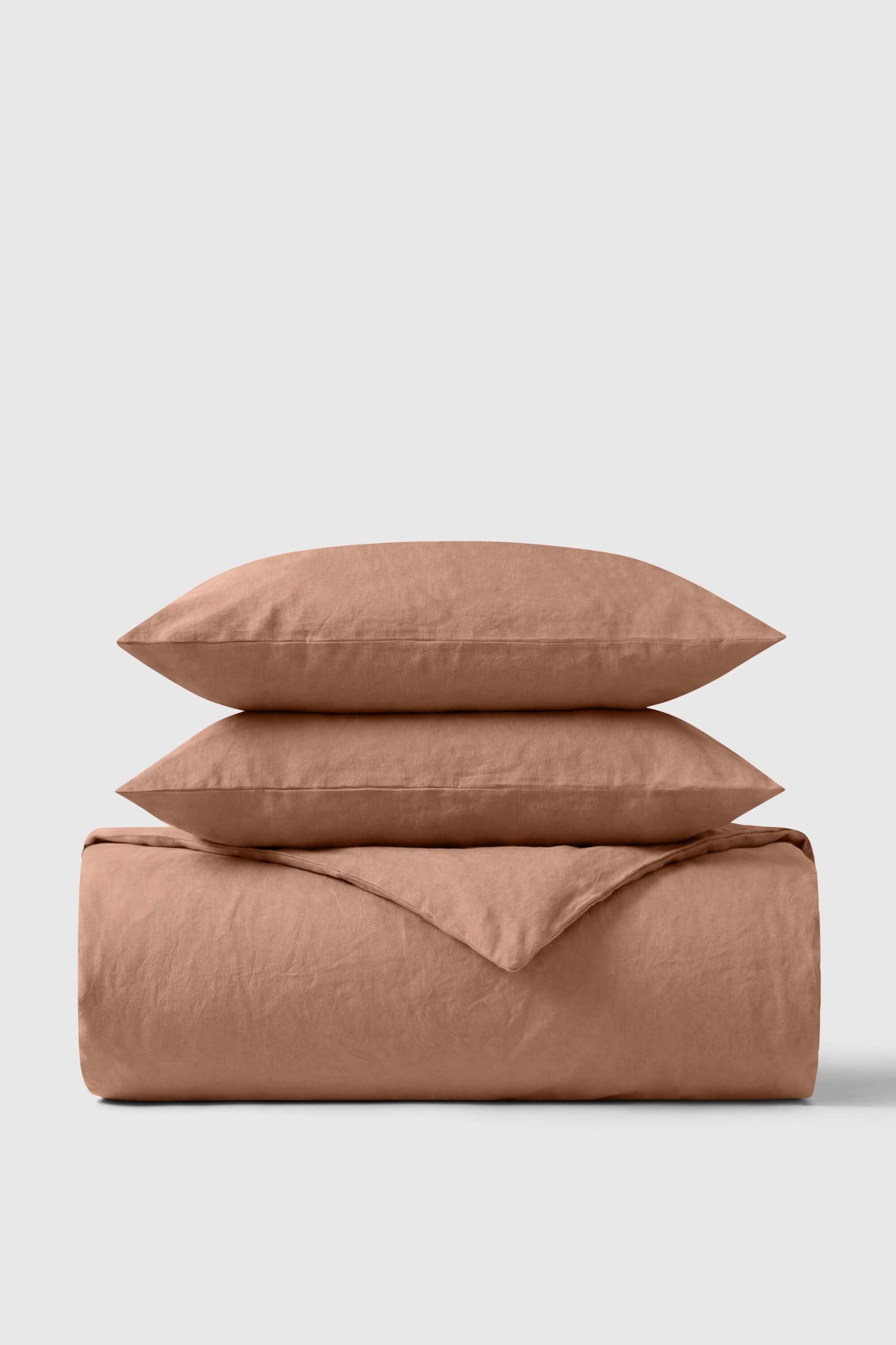 A soft dusty rose percale duvet cover set with two matching pillows made of breathable linen