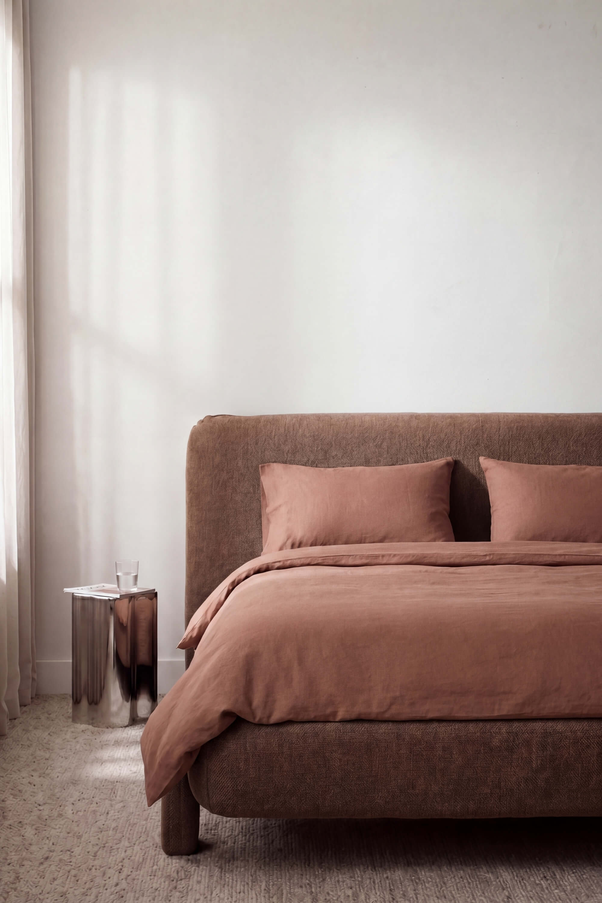 A plush taupe upholstered bed with matching headboard and pillows in the percale essentials bedding set