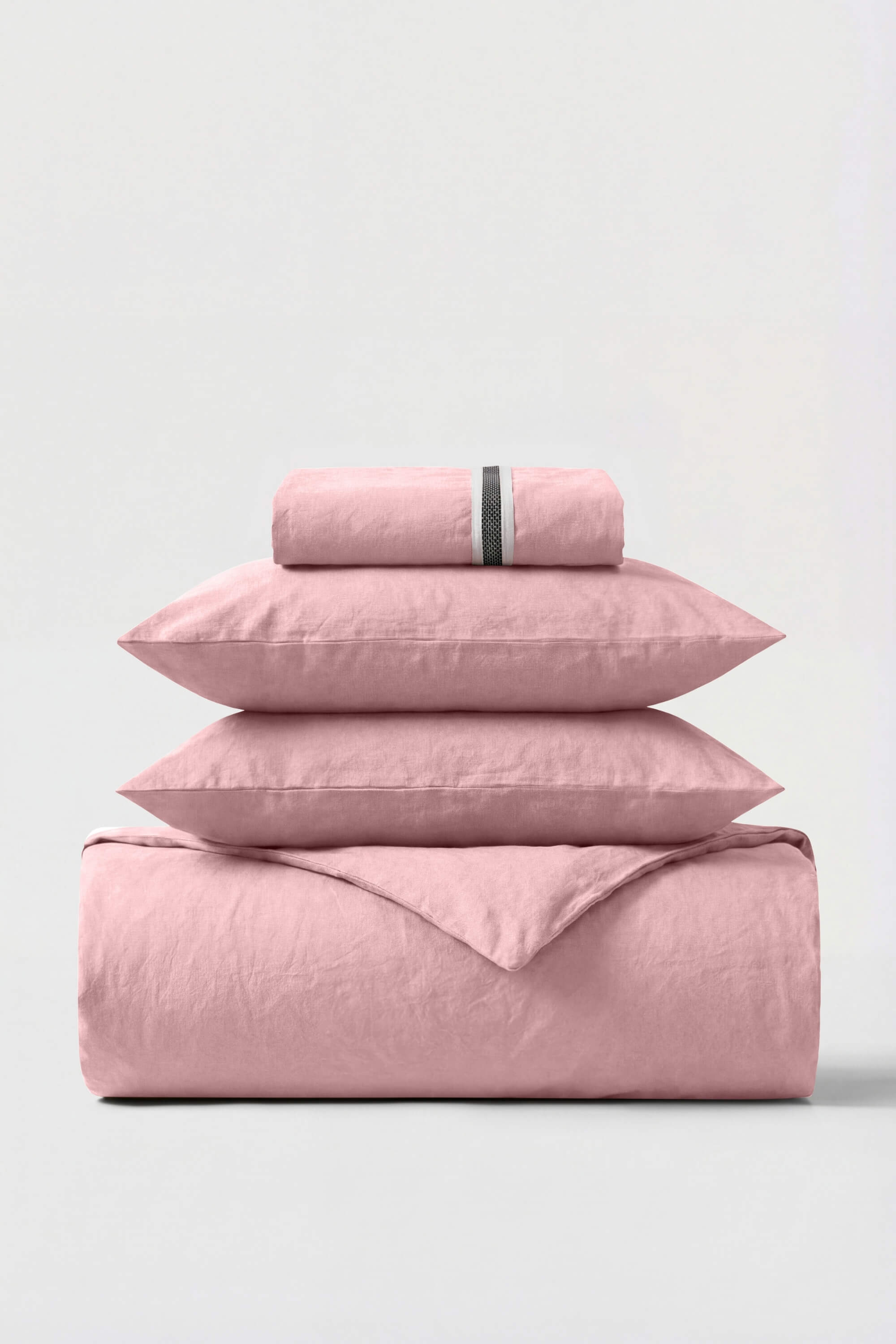 A soft pink percale essentials bedding set with a subtle textured weave and a thin black stripe on the pillowcase