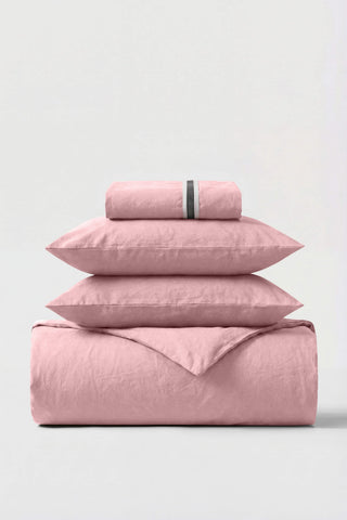 A soft pink percale essentials bedding set with a subtle textured weave and a thin black stripe on the pillowcase