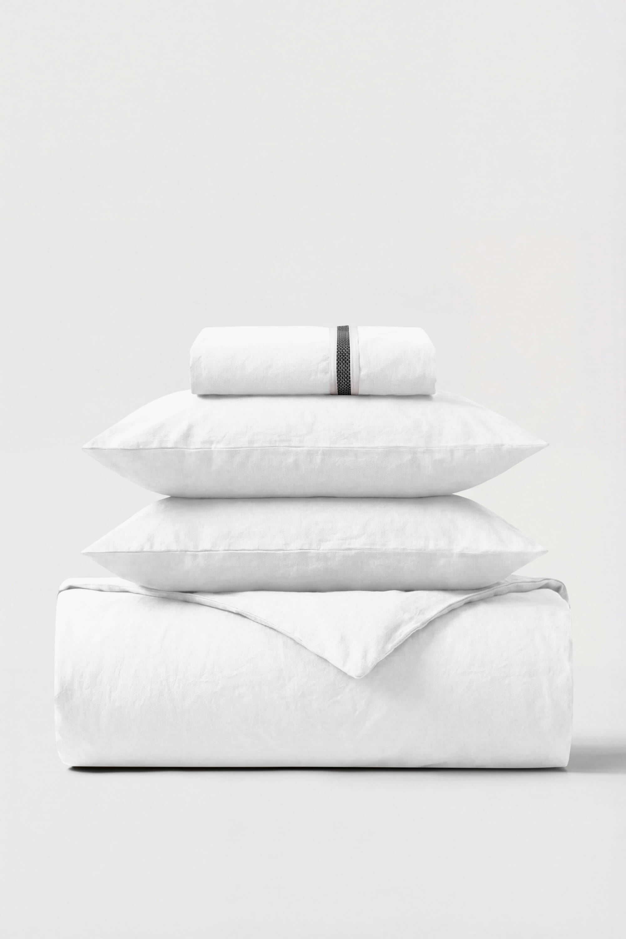 White cotton percale essentials bedding set with subtle black woven band on rolled pillowcase