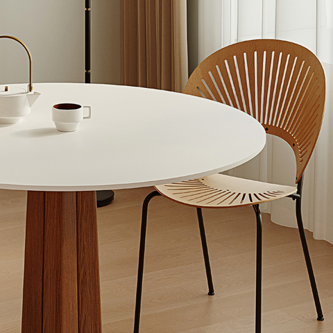 A modern wooden chair with a fan-shaped back and black metal legs paired with a percival white round dining table