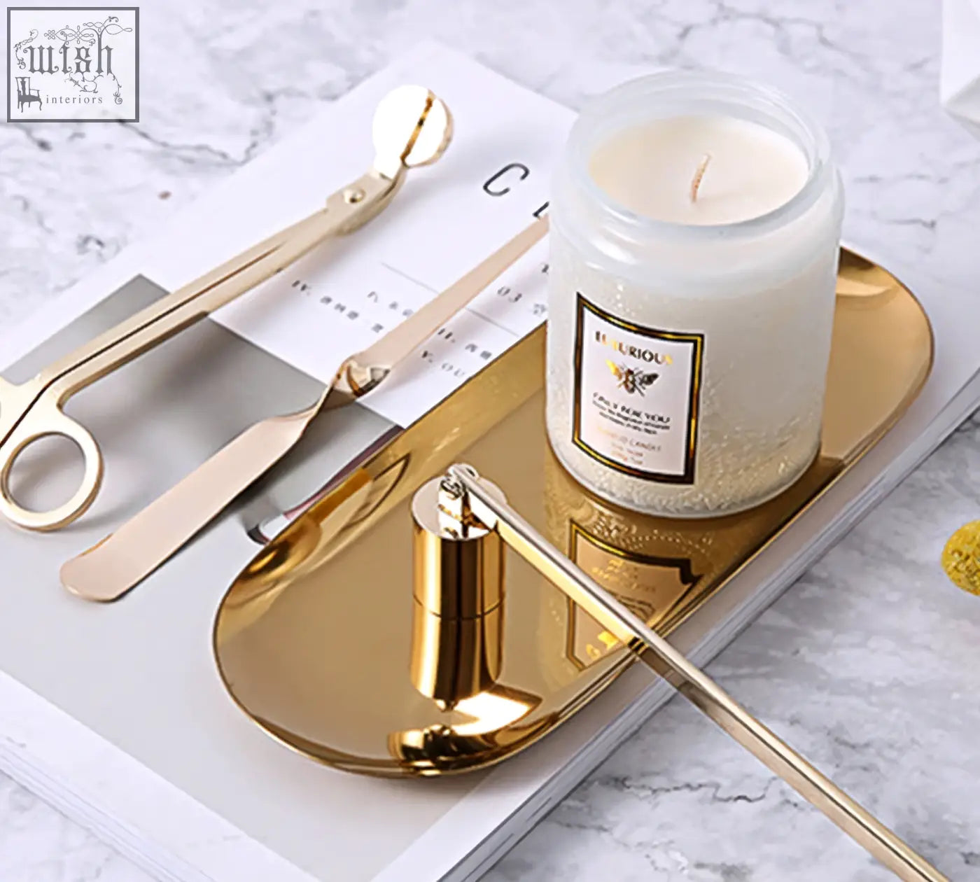 Gold candle snuffer with sleek cylindrical body and long handle resting on tray for peregrine scented candles gift