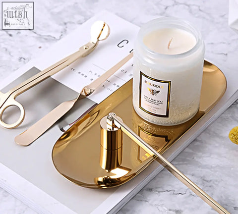 Gold candle snuffer with sleek cylindrical body and long handle resting on tray for peregrine scented candles gift