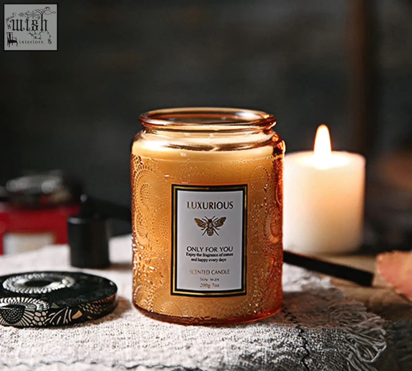 A golden amber glass jar scented candle with embossed patterns and bee label perfect as a candles gift