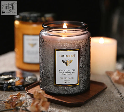 A luxurious silver patterned glass jar candle with lit wick and golden bee label perfect as a scented candles gift