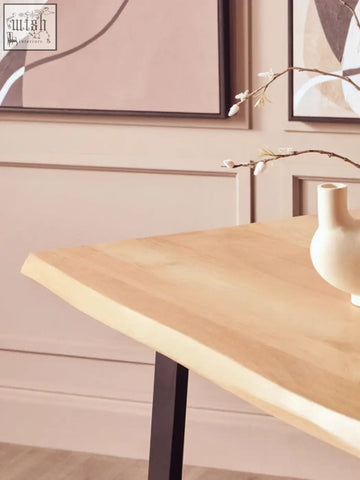 A light-colored mango wood live edge dining table with black metal legs perfect for stylish meals