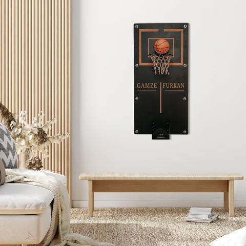 Black wall-mounted personalized mega basketball hoop with brown rim orange ball in net and gold engraved names below