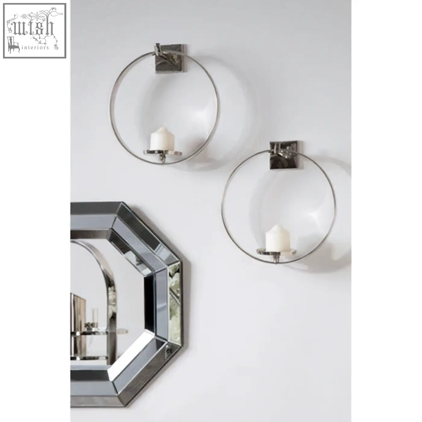 Silver circular wall sconces with clear glass bowls holding white candles next to petillo octagonal wall mirror