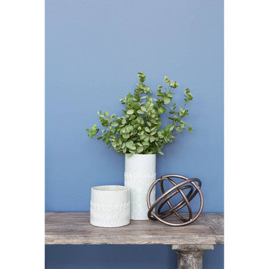 White ceramic petra small planter with subtle embossed texture holding lush green eucalyptus arrangement