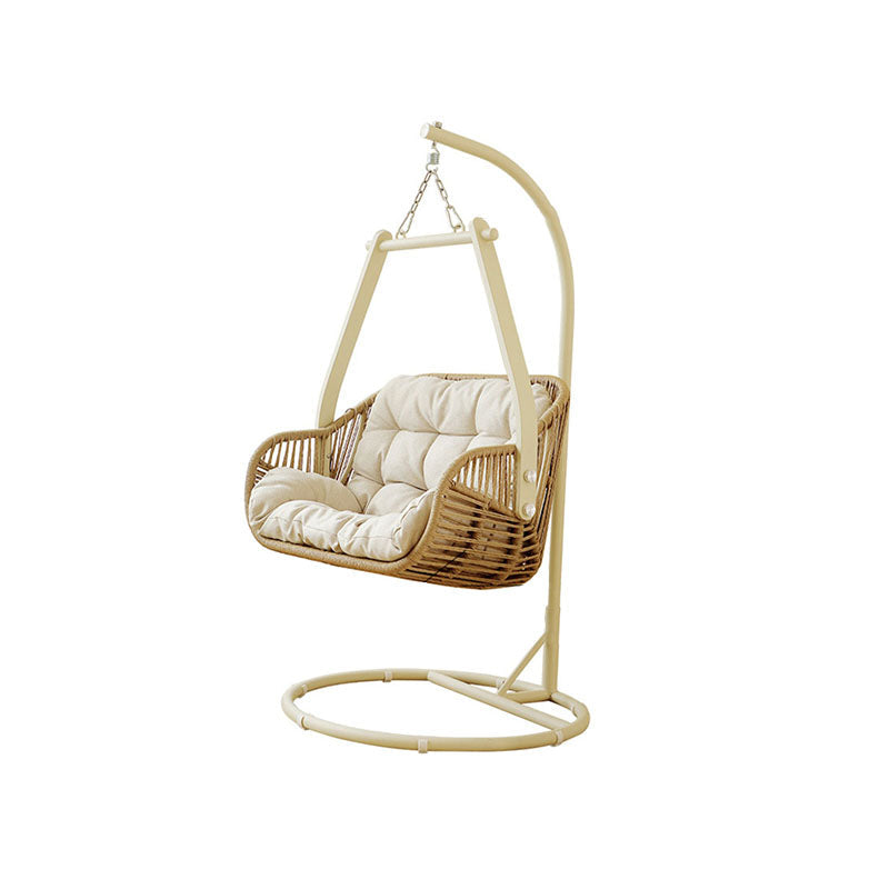 Beige phedra rattan garden hanging egg chair with cushioned seat hanging from arched metal stand for indoor outdoor use