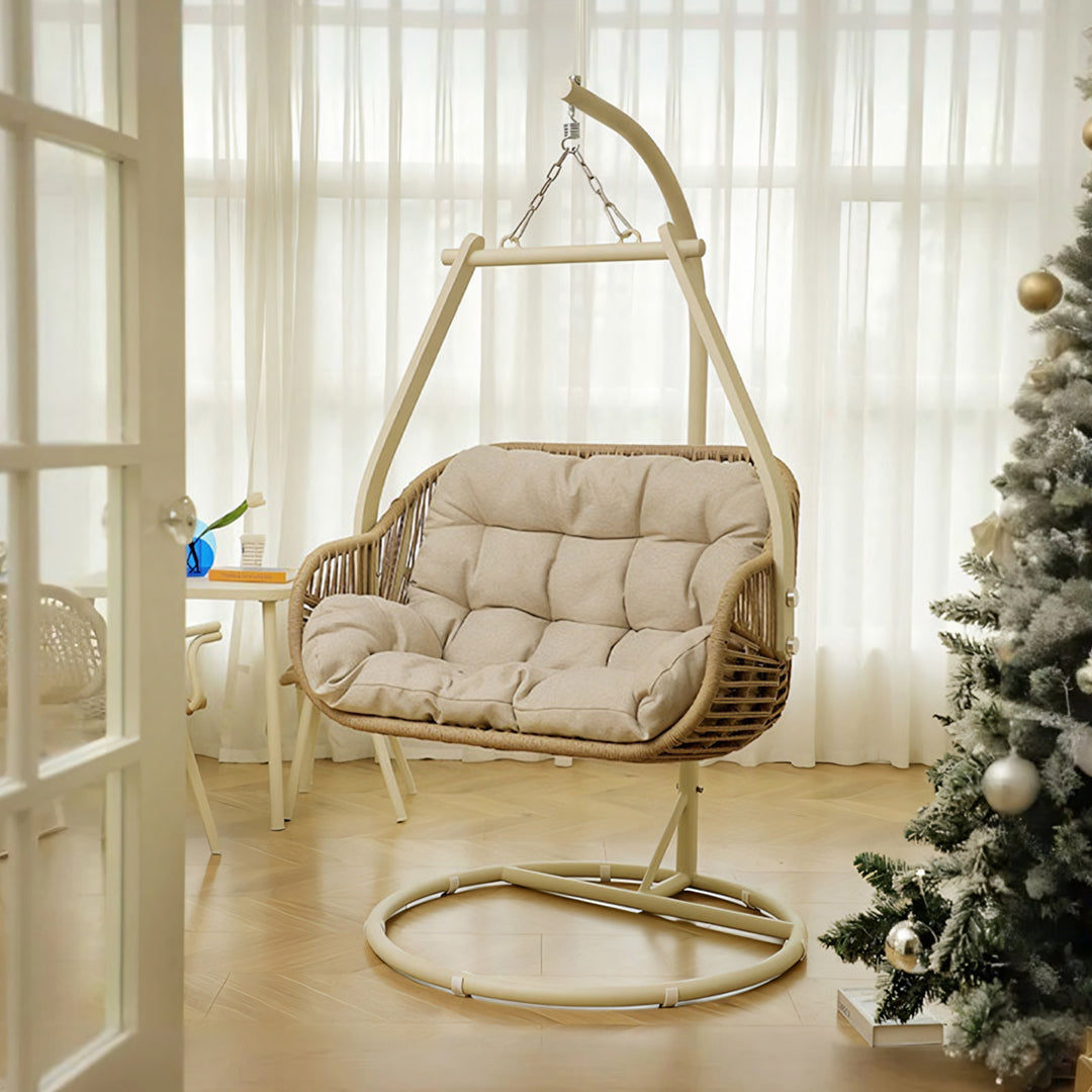 Beige phedra rattan garden hanging egg chair with cushioned seat suspended from arched metal frame for indoor outdoor use