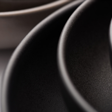 A matte black ceramic pico black coupe plate with smooth textured interior and rounded rim 7 inch size