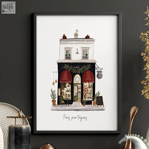 A framed illustration of a parisian café with red awnings and greenery in a black frame from paris pour toujours boutique street scenes