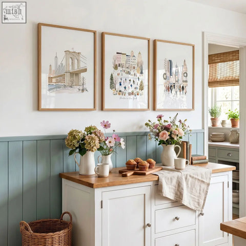 Three beige pastel travel wall art prints of new york winter scenes hang above a wooden kitchen countertop