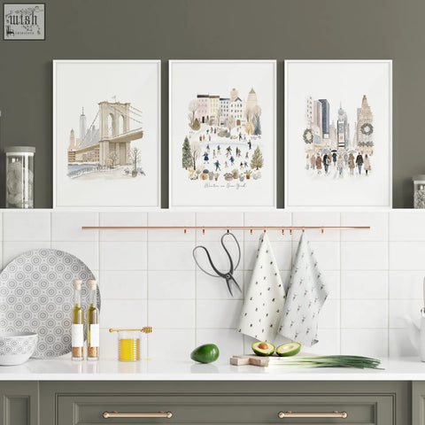 Three framed beige pastel watercolor art prints of new york winter scenes as travel wall art above kitchen counter