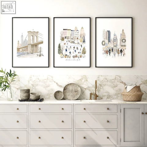 Three framed beige pastel new york winter scenes art prints hang as travel wall art above a marble countertop