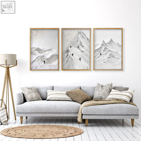 Three black and white mountain climbers wall art prints with light wood frames hanging on living room walls above gray sofa