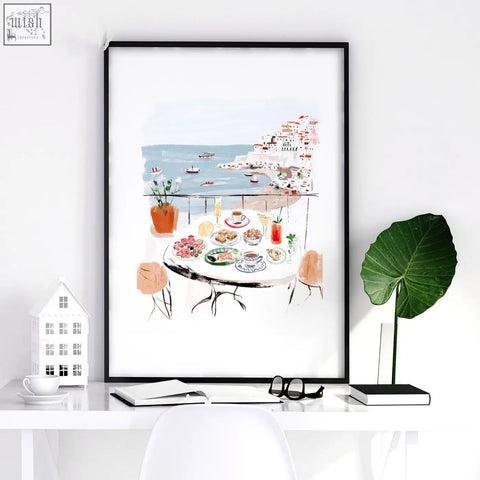 Black-framed watercolor wall art print of sotto il sole seaside café scene with pastel buildings and turquoise water