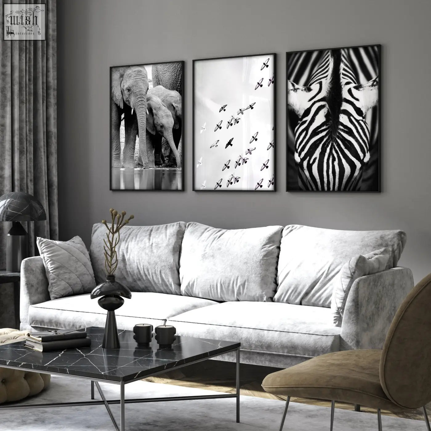 Gray velvet sofa with plush cushions in front of black and white wildlife safari art prints on a living room wall
