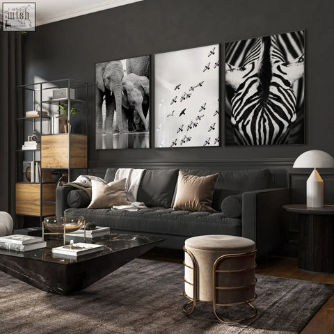 Dark gray velvet sofa with beige and taupe pillows under black and white wildlife safari art prints on living room wall