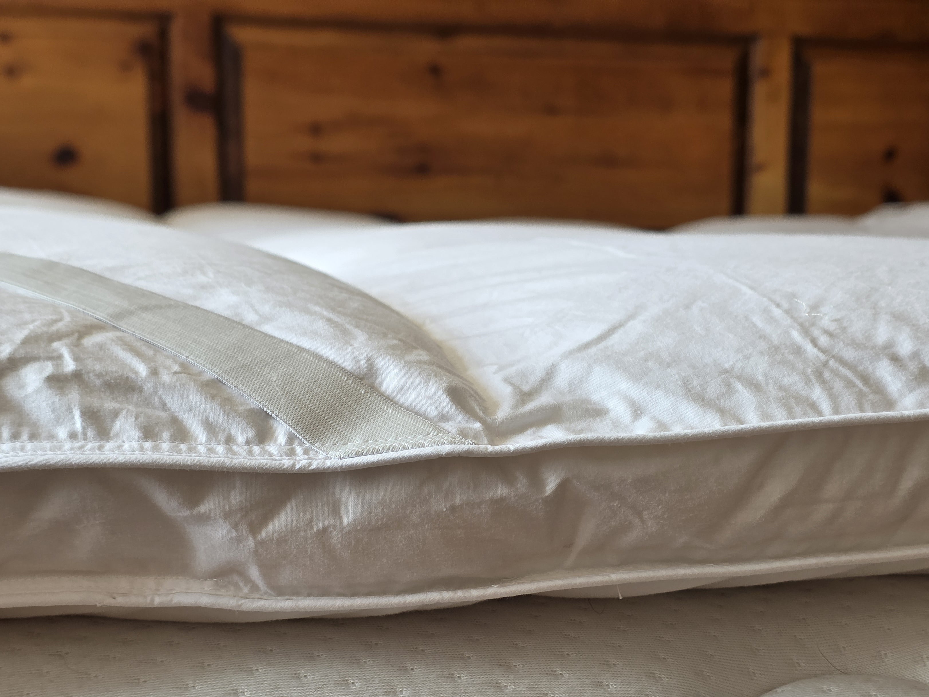 White quilted mattress topper with silver satin stripe made from duck feather for comfy sleep solutions
