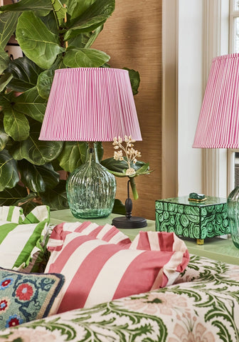 Pink pleated lampshade on textured green glass base paired with pink candy cabana stripe ruffled cushion cover