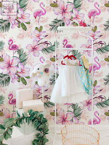 White children’s dress with ruffled skirt hanging next to pink flamingo floral traditional paper for pink nursery living space