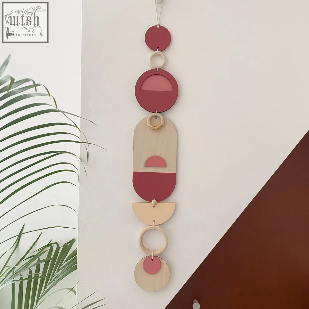 A modern wall art featuring layered wooden circles and half circles with soft pink accents for home decor