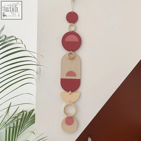 A modern wall art featuring layered wooden circles and half circles with soft pink accents for home decor