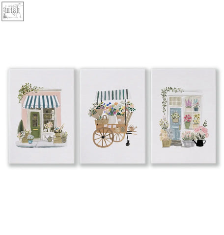 Set of 3 pink picture flower shop art prints featuring pastel buildings and vibrant floral arrangements in wicker baskets