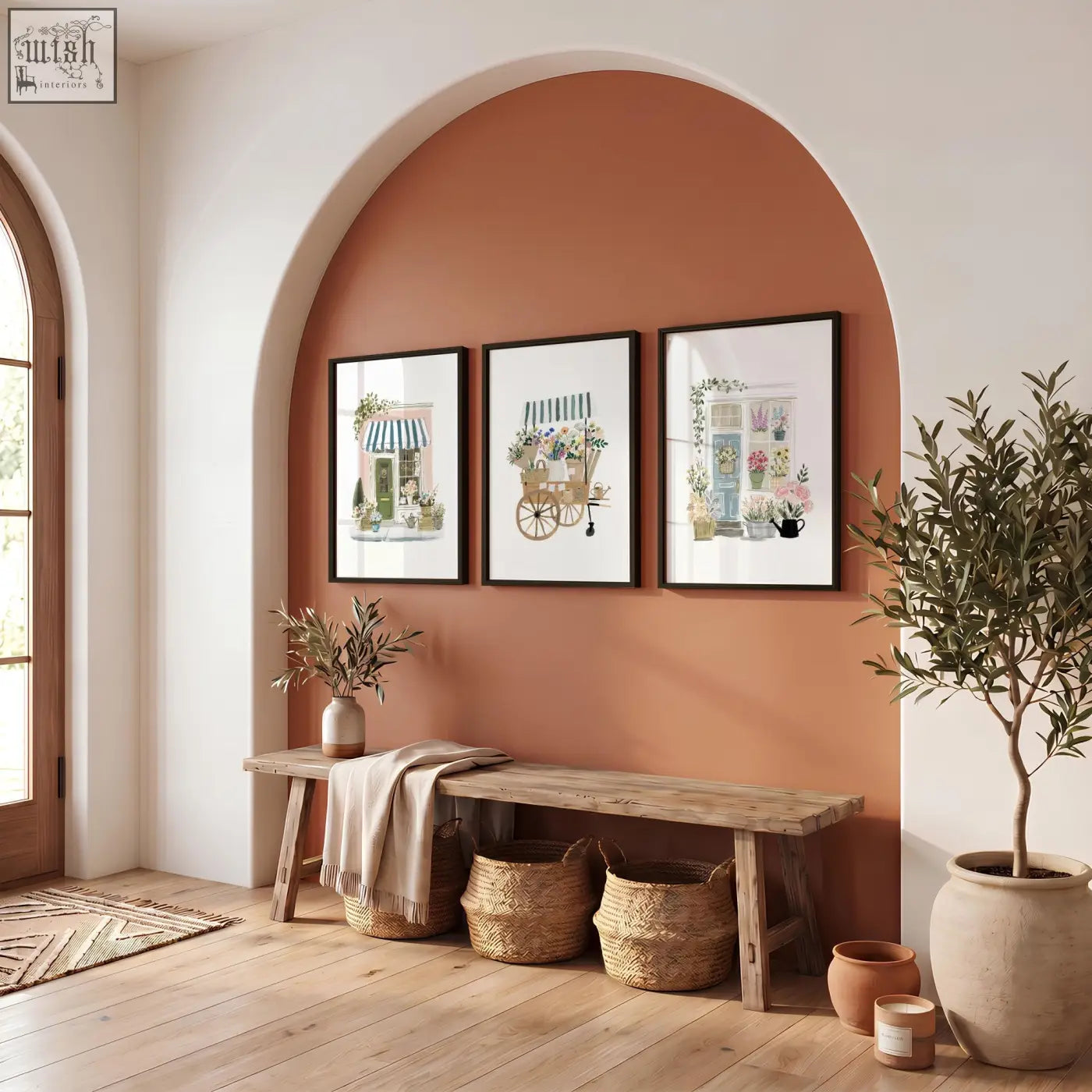 Three pink picture botanical flower shop art prints hang above a rustic bench on an arched terracotta wall
