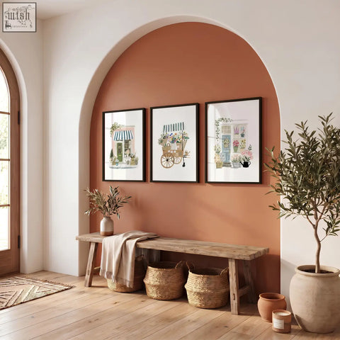 Three pink picture botanical flower shop art prints hang above a rustic bench on an arched terracotta wall