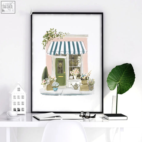 A framed pink picture art print of a charming flower shop with teal striped awning and green door perfect wall art