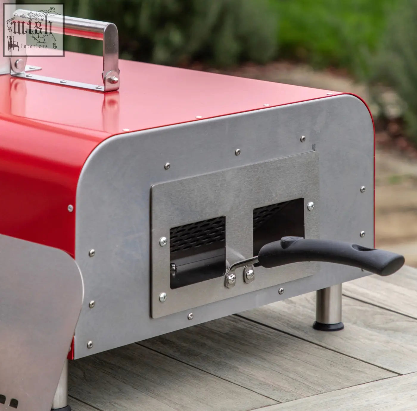 Red and silver portable pizza oven table top with stainless steel body, handle, two vents, and black side lever