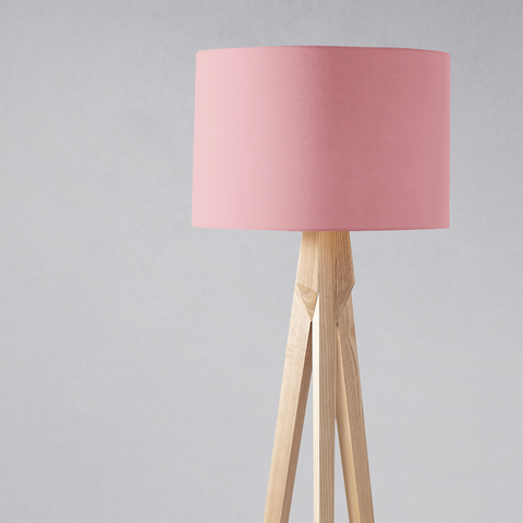 A plain dusty rose lampshade in soft pink mounted on a light wooden tripod base perfect for a table lamp