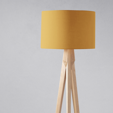 A plain mustard cylindrical lampshade on a light wooden tripod base for table lamp use