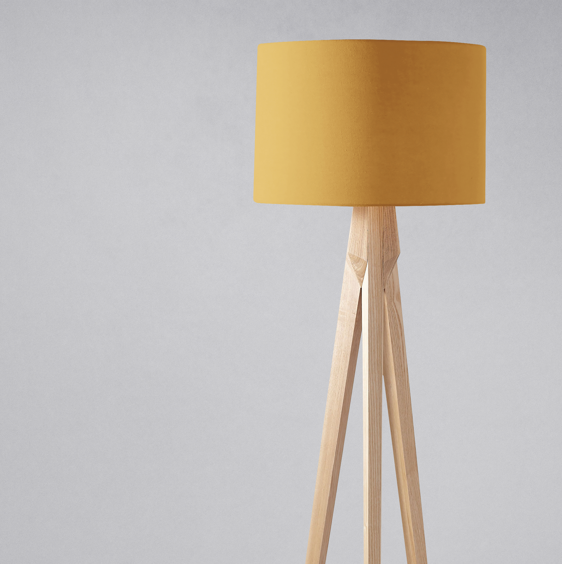 A plain mustard lampshade made of fabric on a light wooden tripod base perfect for a table lamp