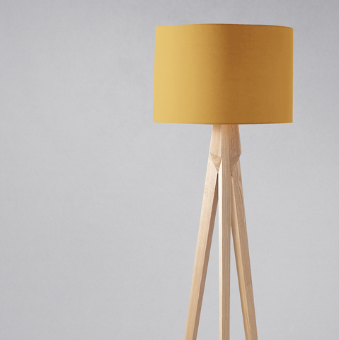 A plain mustard lampshade made of fabric on a light wooden tripod base perfect for a table lamp