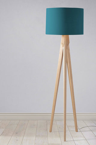 A plain teal lampshade on a minimalist light wood tripod base perfect as a table lamp shade