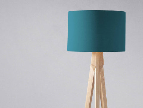 Plain teal lampshade with a teal cylindrical shade on a light wooden tripod base ideal for a table lamp