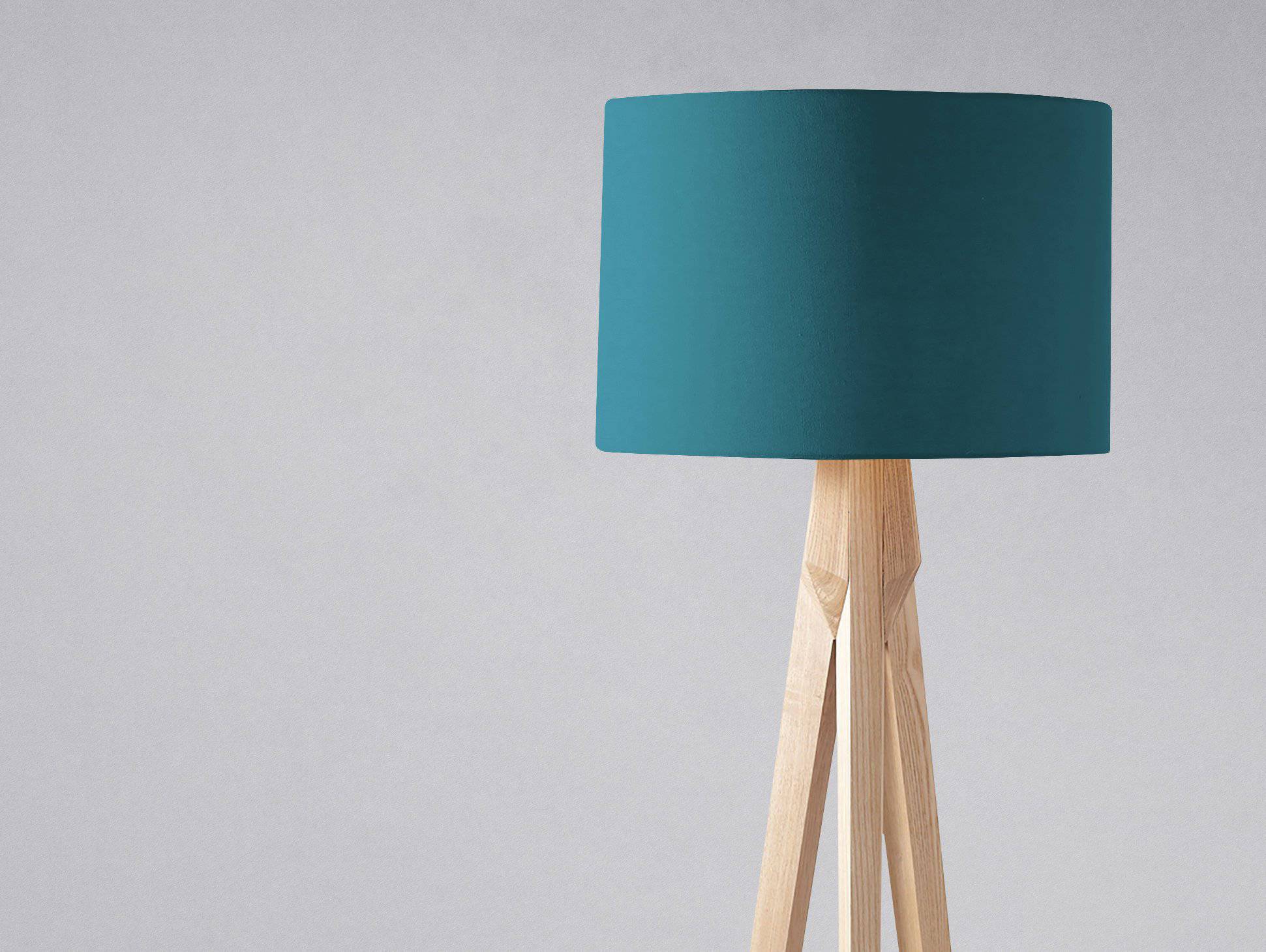 Teal cylindrical plain teal lampshade mounted on a light wooden tripod base perfect for table lamp use