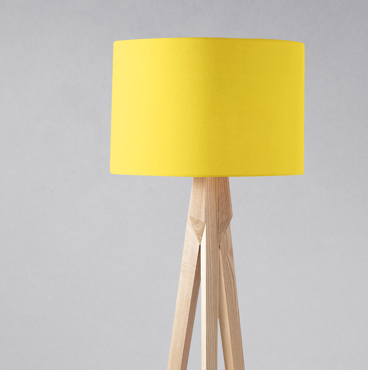 Bright yellow plain yellow lampshade on a light wooden tripod base perfect for table lamp use