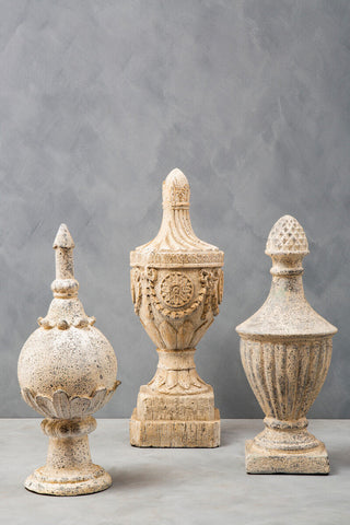 Three weathered off-white stone effect urns with intricate carvings from the plato light stone collection