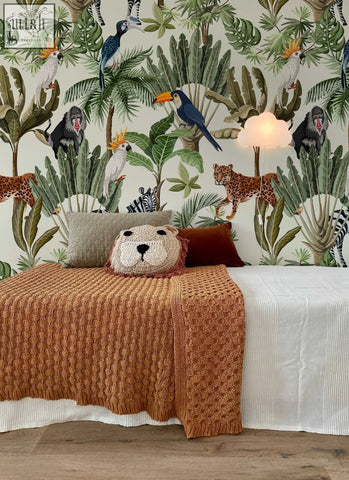 A cozy orange knitted lion pillow with a soft plush face and embroidered nose for playful jungle animals nursery decor