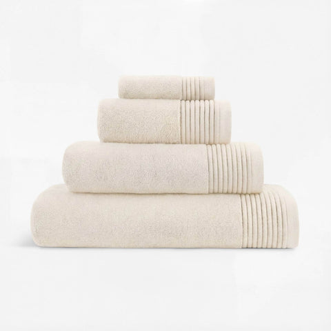 Stack of cream-colored plush towels made of soft cotton with ribbed edges for a cozy bathroom touch