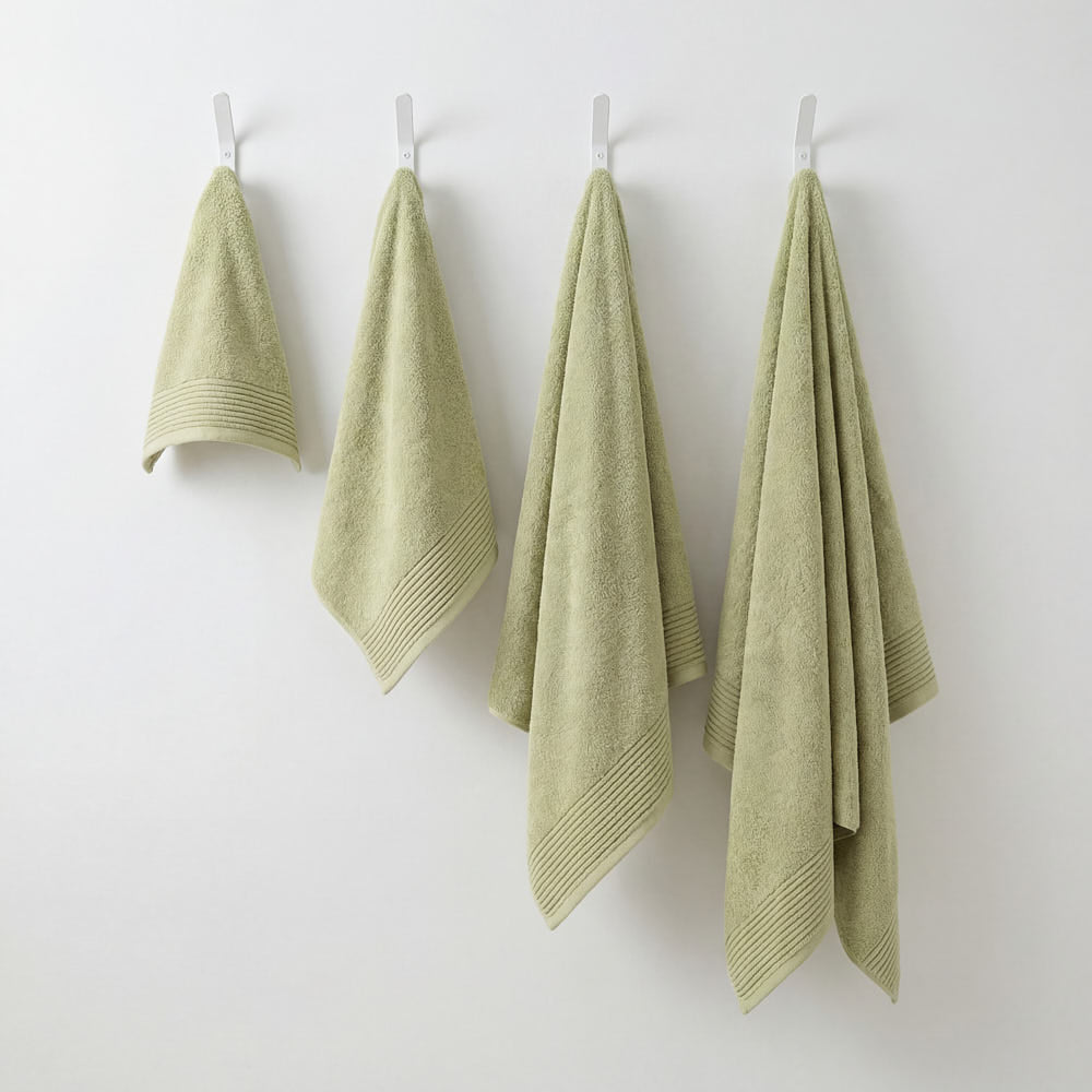 Four pale green plush towels with ribbed hemmed edges hanging neatly on white hooks