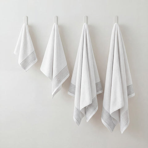 White cotton plush towels set with subtle gray striped trim hanging neatly on hooks for bathroom use